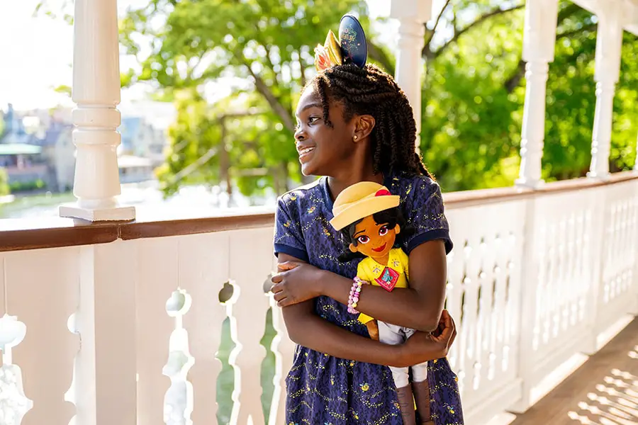 Girl smiling in Tiana's Bayou Adventure apparel holding Tiana plush