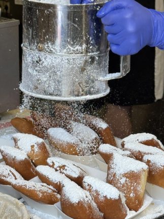Tiana's Famous Beignets getting dusted with powdered sugar