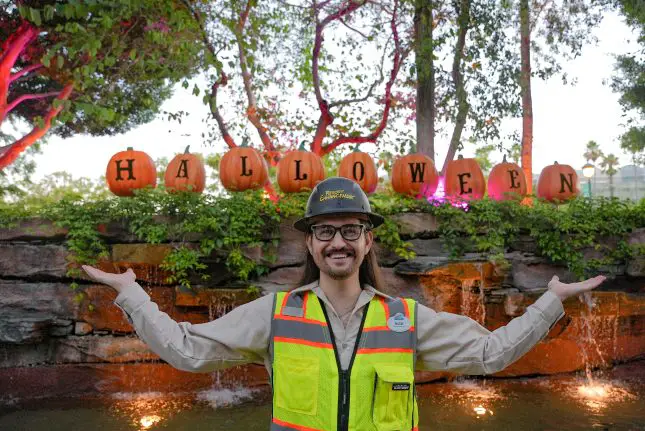 Resort Enhancement cast member, Nick Stauf, cheerfully poses with pumpkins on display in Downtown Disney District.