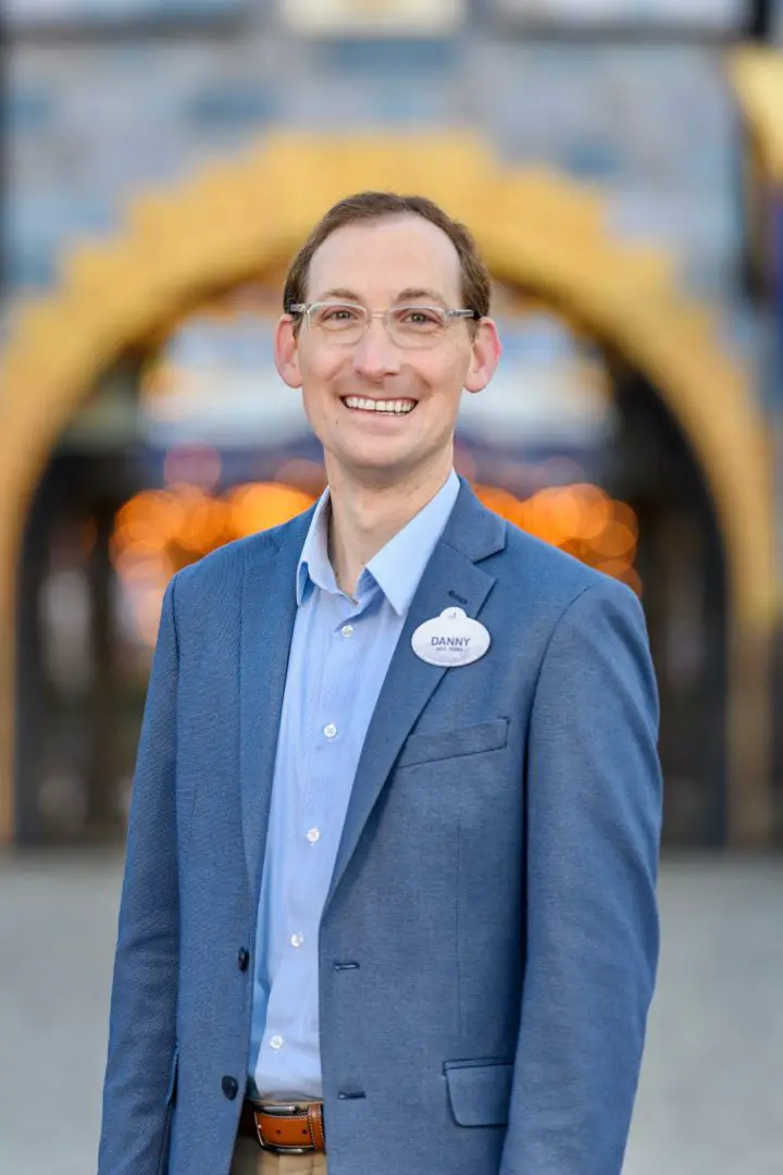 Danny Chase stands in front of Sleeping Beauty Castle in Disneyland park.