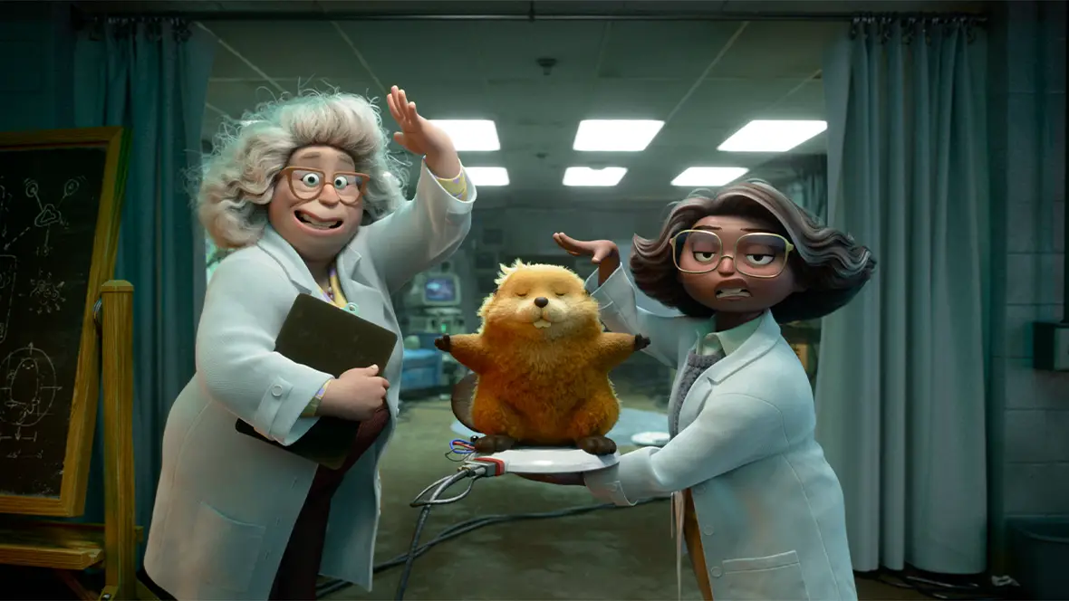 In a still from Disney and Pixar’s Hoppers, Dr. Sam (voiced by Kathy Najimy), left, and Nisha (voiced by Aparna Nancherla), right, are standing in a lab; Dr. Sam is gesturing to her own head, while Nisha is holding a robotic beaver on a small platform and gesturing to it.